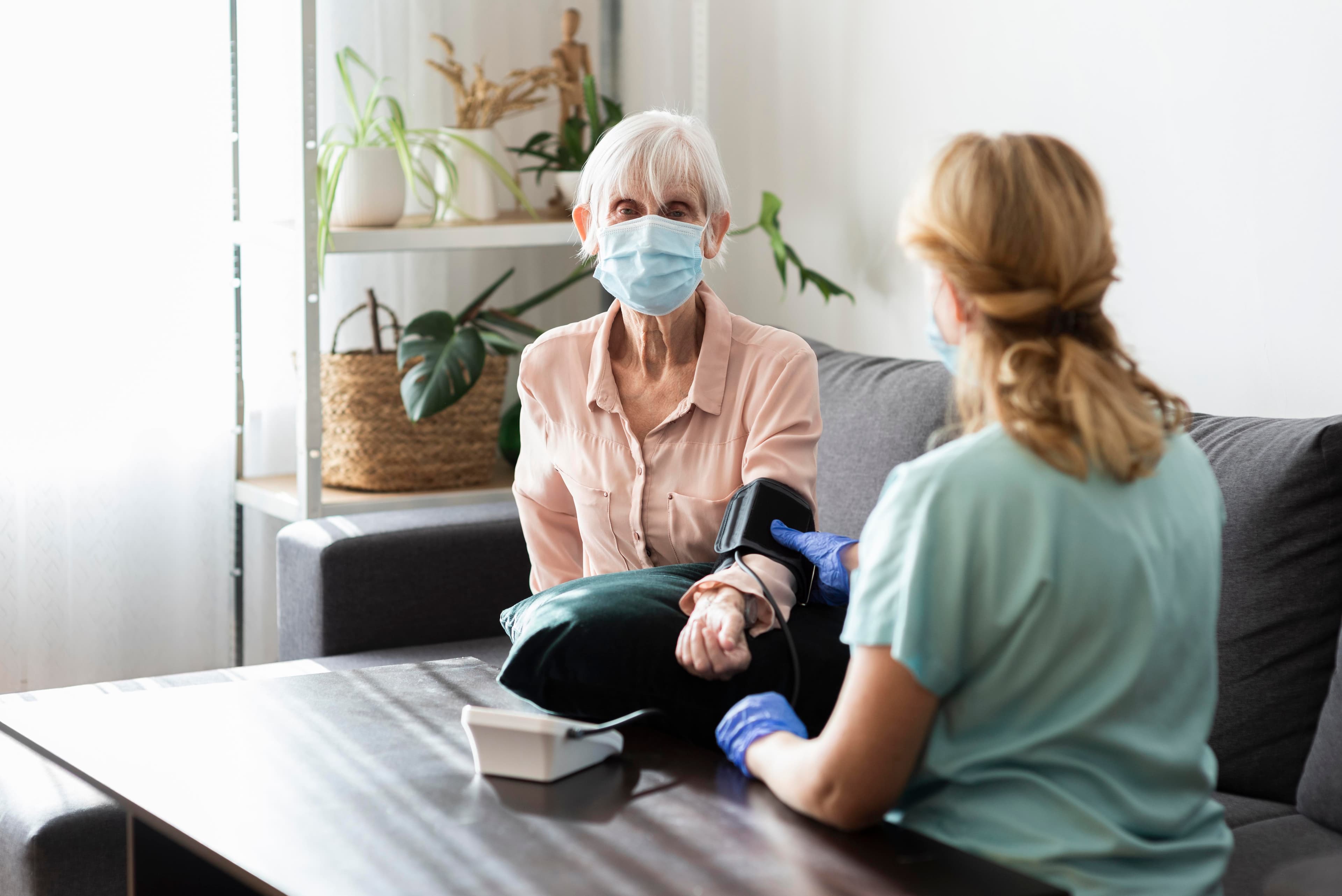 Elder woman with medical mask having her blood pressure checked